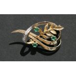 A 9ct gold diamond and emerald brooch of naturalistic form.