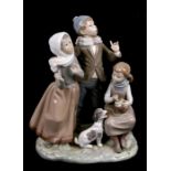 A Lladro group depicting children singing with a puppy, 19cms (7.5ins) wide.Condition ReportLoss