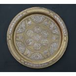 An Islamic bronze charger with silver and copper overlay including script and stylised foliate