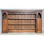 A George III oak dresser rack with three central shelves flanked by cupboards, 231cms (91ins) wide.