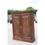 An oak cupboard with two panelled doors enclosing a shelved interior, on a plinth base, 102cms (