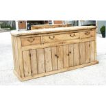 A large Victorian pine dresser base with three frieze drawers with cupboards beneath, on a plinth