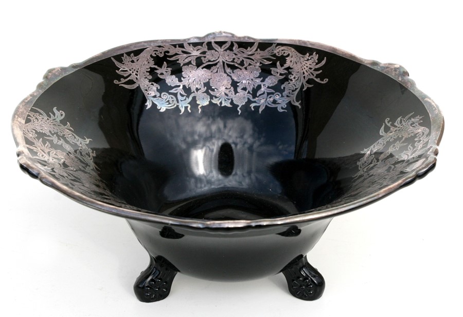 A black glass three-footed bowl with silvered inlay, 27cms (10.5ins) diameter.