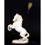 A ceramic table lamp in the form of a rearing horse, on a gilt metal base, 33cms (13ins) high.