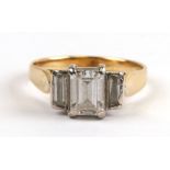 A yellow metal (tests as gold) dress ring set with three baguette cut clear stones, approx UK