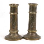 A pair of Islamic brass candlesticks with pierced decoration, 23cms (9ins) high.