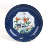 A Chinese plate, the central panel decorated with flowers and insects on a blue ground, character