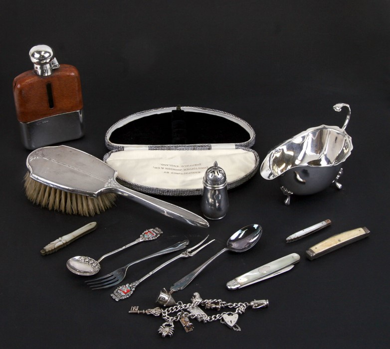 A silver sauce boat, a silver mounted hip flask,a silver back brush, a silver charm bracelet and