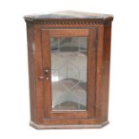 A 19th century oak corner cupboard with astragal glazed door, 63.5cms (25.5ins) wide.