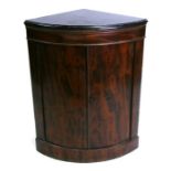 A floor standing bowfronted corner cupboard with black marble top, 69cms (27ins) wide.