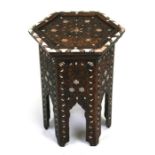 An Islamic octagonal wooden table inlaid with mother of pearl and bone, 32cms (13ins) wide.