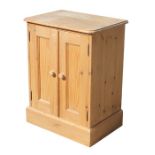 A pine cupboard with twin panelled doors, on a plinth base, 59cms (27ins) wide.