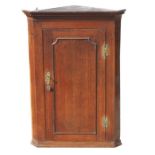 A George III large oak corner cupboard with single panelled door, enclosing three shelves, 76cms (