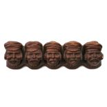 A Black Forest style carved pipe rack, carved heads with various expressions, 35cms (13.75ins)