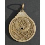 A Persian brass astrolabe of typical form containing three plates, 5.5cms (2.1ins) diameter.