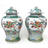 A pair of Chinese famille rose baluster vases and covers decorated with figures in a seascape, 40cms