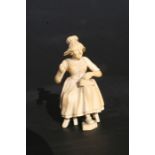 A 19th century Dieppe ivory figure depicting an old woman sat on a stool mending a shoe, 10cms (