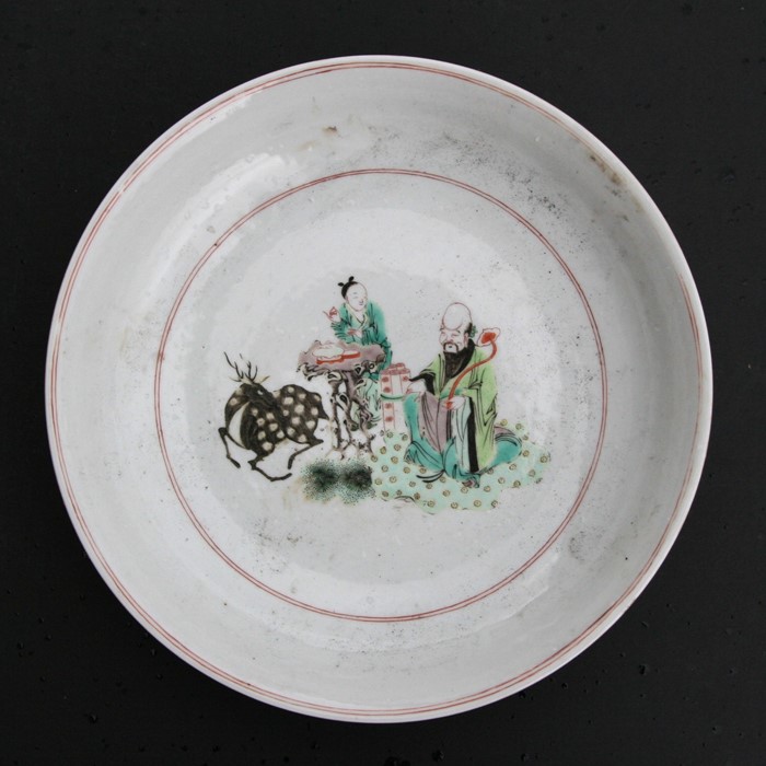 A Chinese famille rose charger depicting a scholar with scrolls beside a scribe and a deer, 30cms (