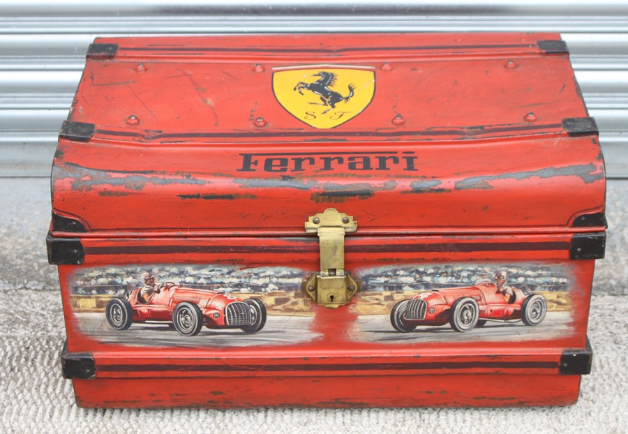 A vintage tin trunk, later decorated with a Ferrari Prancing Horse emblem and two Monoposto