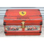 A vintage tin trunk, later decorated with a Ferrari Prancing Horse emblem and two Monoposto