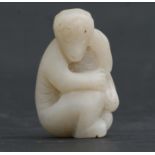A Chinese mutton fat white jade figure carved in the form of a seated monkey, 5cms (2ins) high.