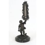A bronze figural desk top thermometer in the form of a young boy carrying a sickle and holding a