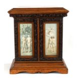 A carved oak table cabinet, the pair of glazed doors decorated prints depicting Adam and Eve