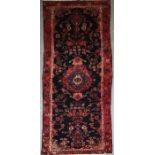 A Persian hand knotted woollen Hamadan runner with central gul and stylised flowers within a