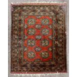 A Persian Turkoman rug with repeated geometric design on a red ground,