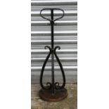 A wrought iron door stop of scroll form on a circular base, 64cms (25ins) high.
