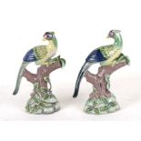 A pair of Chinese style pottery birds perched on tree stumps, 23cms (9ins) high.