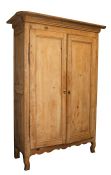 A French pine armoire with two panelled doors on a shaped apron base, 127cms (50ins) wide.