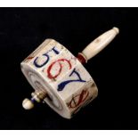 A 19th century bone spinning top teetotum having numbered edges and painted decoration. 6.5cm (2.5