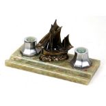 An Art Deco onyx inkstand with two lidded inkwells flanking a metal model of a sailing ship, 25.5