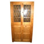 A Monk Man Arts & Crafts style oak free-standing corner cupboard with a pair of astragal glazed