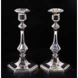 A pair of Edwardian silver candlesticks, each with slender baluster form columns on stepped