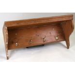 A pine hanging shelf with four brass coat hooks beneath, 92cms (36ins) wide.