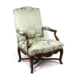 A 17th century style upholstered open arm chair, the front apron with carved decoration, joined by