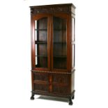 A continental oak glazed display cabinet, the pair of doors enclosing a shelved interior with two