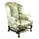 An 18th century style upholstered wing back armchair on shell capped dwarf cabriole legs, with pad