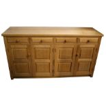 A Monk Man Arts & Crafts style oak sideboard with four drawers above two pairs of panelled doors, on