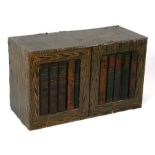 A table top cabinet with book spine decorated doors, enclosing an arrangement of cupboards, 64cms (