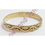 A 9 carat gold bangle, with applied acorn and oak leaf decoration, inner diameter approximately 6.