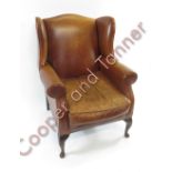 A modern brown leather wingback armchair