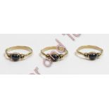 A trio of 9 carat gold single stone sapphire rings, each set with a cabochon between a trefoil of