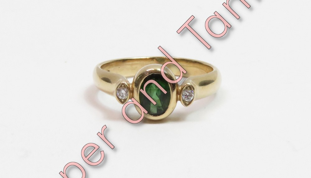 A 9 carat gold green tourmaline and diamond three stone ring, the oval cut with a brilliant cut