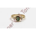 A 9 carat gold green tourmaline and diamond three stone ring, the oval cut with a brilliant cut