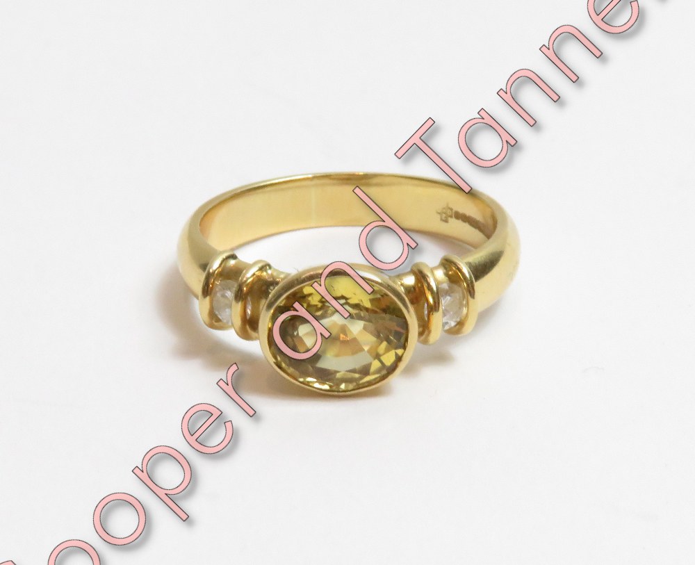 An 18 carat gold yellow sapphire and diamond ring, the oval cut with a diamond to each shoulder,