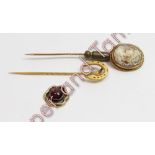 A shell cameo stickpin; a horseshoe stickpin; and a small garnet set pendant