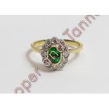 A green tsavorite and diamond 18 carat gold cluster ring, the oval cut stone enclosed by twelve